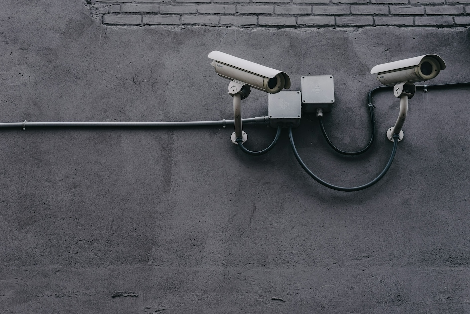 Close-up of two security cameras on a gray wall.